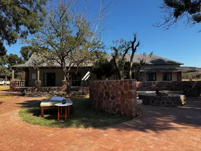 a house with a brick yard with a table in front of it at Welgedacht Lodge in Cullinan