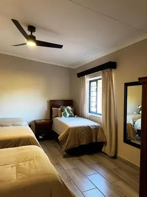 a bedroom with two beds and a ceiling fan at Welgedacht Lodge in Cullinan