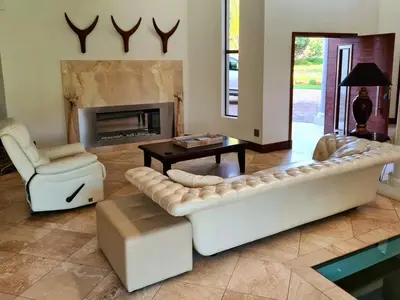 a living room with a couch and a table and a fireplace at The Villa Luxe Hartbeespoort Golf and Wildlife Estate in Hartbeespoort