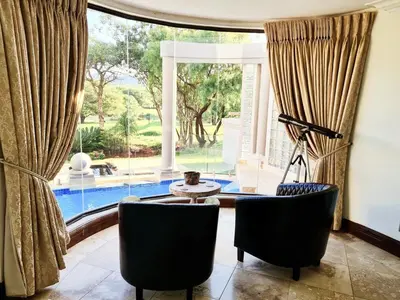 a living room with two chairs and a large window at The Villa Luxe Hartbeespoort Golf and Wildlife Estate in Hartbeespoort
