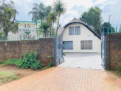 a white house with a gate and a brick fence at Harmony Spaces in Kempton Park