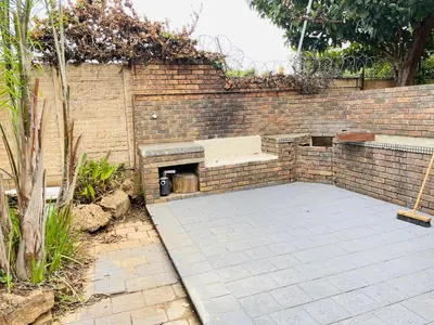 a brick wall with a bench in a courtyard at Harmony Spaces in Kempton Park