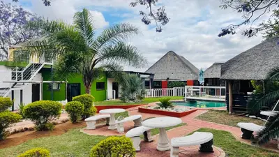 a courtyard with tables and benches and a pool at De whytehouse Mogalatsane in Marble Hall