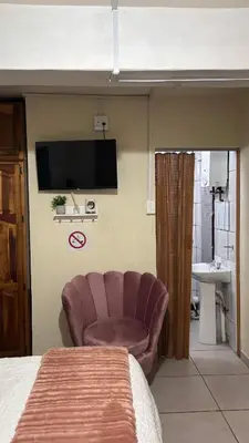 a bedroom with a chair and a television on the wall at Harmony Spaces in Kempton Park