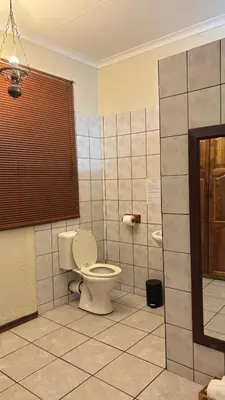 a bathroom with a toilet and a tiled floor at Harmony Spaces in Kempton Park