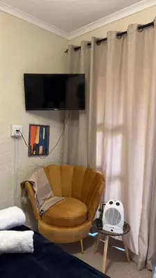 a living room with a chair and a tv at Harmony Spaces in Kempton Park