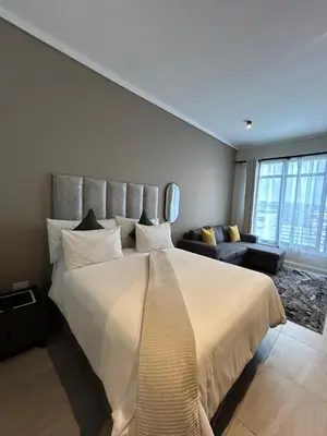 a bedroom with a large white bed and a couch at The Capital Trilogy Menlyn Maine Apartment in Pretoria