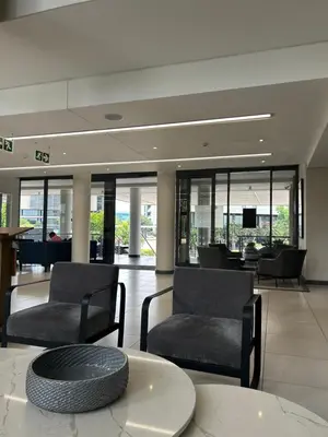 a lobby with chairs and a table in a building at The Capital Trilogy Menlyn Maine Apartment in Pretoria