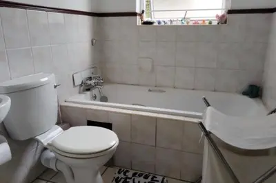a bathroom with a white toilet and a bath tub at Sunninghill apartment in Sandton