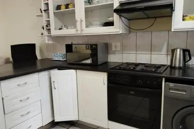 a kitchen with white cabinets and a black stove top oven at Sunninghill apartment in Sandton