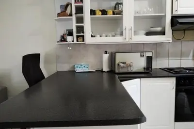 a kitchen with a black counter top and white cabinets at Sunninghill apartment in Sandton