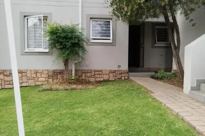 a house with a grass yard in front of it at Sunninghill apartment in Sandton