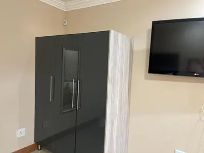 a black cabinet with a television on a wall at Private Room with patio 2 in Mokopane