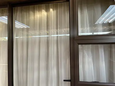a pair of glass windows with white curtains at Private Room with patio 2 in Mokopane