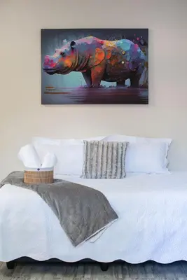 a painting of an elephant on a wall above a bed at Hippo's Rest in Ellisras