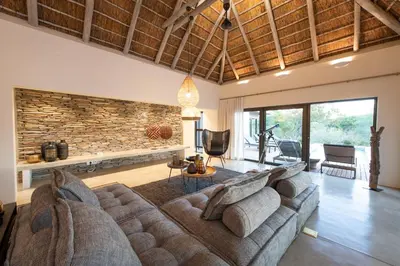 a living room with a large couch and a stone wall at Villa Aloe Vera in Hoedspruit