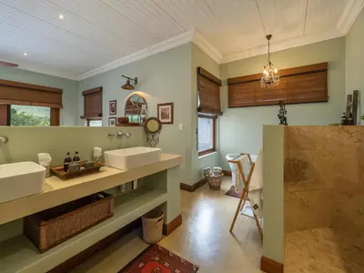 a bathroom with two sinks and a mirror at Kambaku River Lodge in Malelane