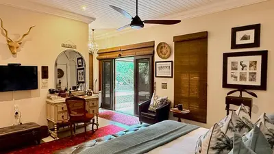 a living room with a bed and a desk and a television at Kambaku River Lodge in Malelane