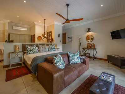 a large bedroom with a bed and a couch at Kambaku River Lodge in Malelane