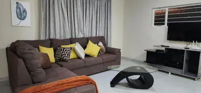 a living room with a brown couch with yellow pillows at 66 On RN in Midrand