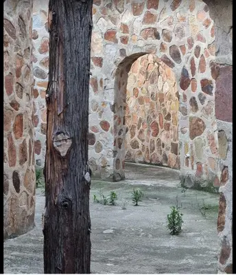 a stone building with a tree and an archway at Stone Cottage in Waterval Boven