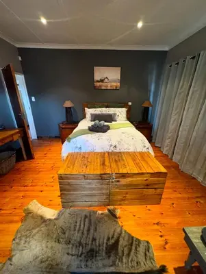 a bedroom with a bed and a wooden floor at Stone Cottage in Waterval Boven