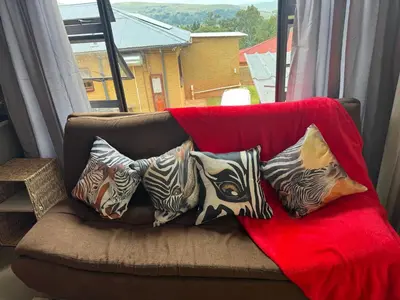 a couch with pillows on it with a window at Stone Cottage in Waterval Boven