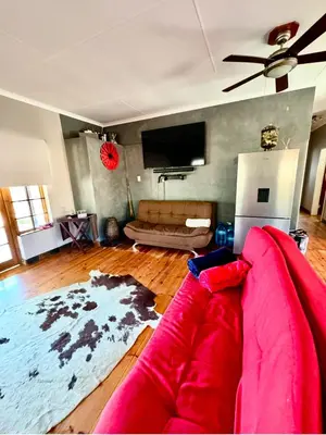 a living room with a red couch and a flat screen tv at Stone Cottage in Waterval Boven