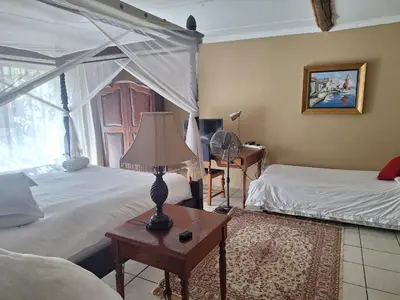a bedroom with two beds and a lamp on a table at Bosveld Gastehuis Bosveld Guesthouse
