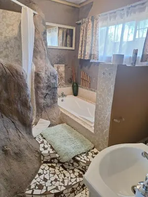 a bathroom with a bath tub and a sink at Bosveld Gastehuis Bosveld Guesthouse