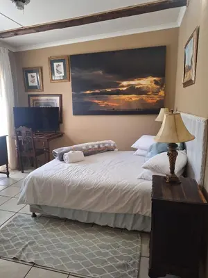 a bedroom with a bed with a painting on the wall at Bosveld Gastehuis Bosveld Guesthouse