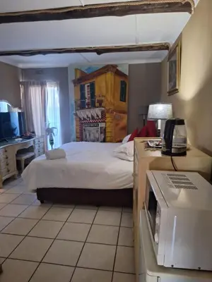 a bedroom with a bed and a microwave at Bosveld Gastehuis Bosveld Guesthouse
