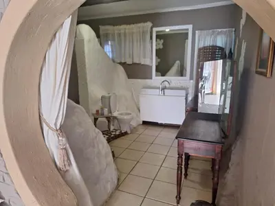 a bathroom with a sink and a toilet and a mirror at Bosveld Gastehuis Bosveld Guesthouse