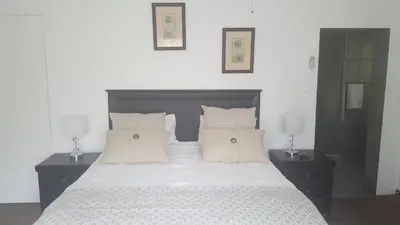 a bedroom with a bed with white sheets and pillows at Spring Acres Guesthouse in Nelspruit