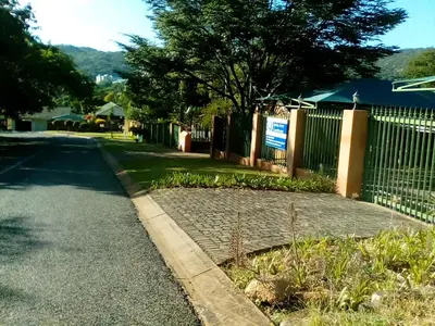a fence next to a street with a cobblestone road at Spring Acres Guesthouse in Nelspruit