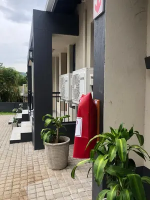 a building with a red cooler and some plants at Spring Acres Guesthouse in Nelspruit