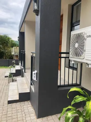 a white air conditioner on the side of a building at Spring Acres Guesthouse in Nelspruit