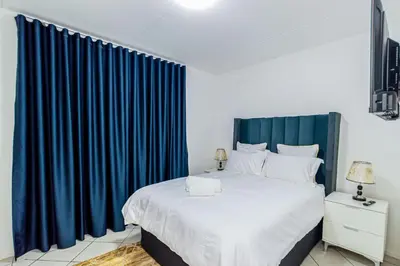 a bedroom with a large bed with blue drapes at The Villa in Midrand