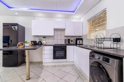 a kitchen with white cabinets and a washer and dryer at The Villa in Midrand