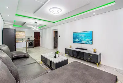 a living room with a couch and a tv on a wall at The Villa in Midrand