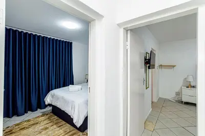a bedroom with a bed and a blue curtain at The Villa in Midrand