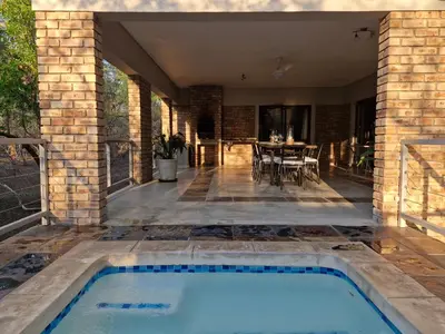 a swimming pool in the middle of a patio with a table at Tusker House Kruger in Marloth Park