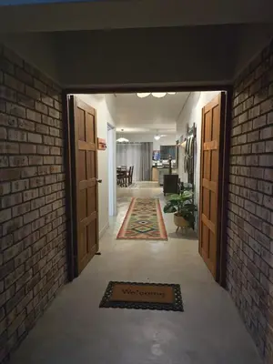 a hallway with two doors and a brick wall at Tusker House Kruger in Marloth Park