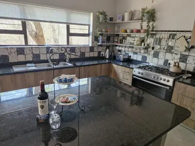 a kitchen with a glass table with a bottle of wine at Tusker House Kruger in Marloth Park