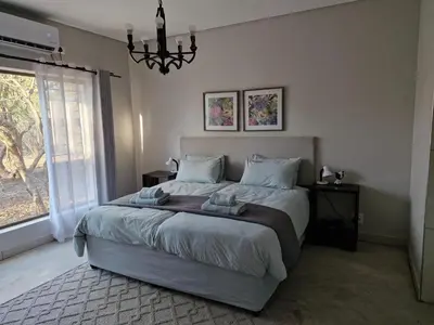 a bedroom with a large bed and a chandelier at Tusker House Kruger in Marloth Park