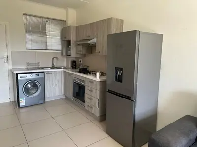 a kitchen with a refrigerator and a washing machine at Luxury Apartment At Erand Gardens Midrand in Midrand