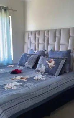 a bed with a blue comforter with flowers on it at Luxury Apartment At Erand Gardens Midrand in Midrand