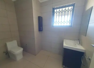 a bathroom with a toilet and a sink and a window at Luxury Apartment At Erand Gardens Midrand in Midrand
