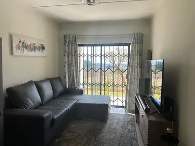 a living room with a couch and a large window at Luxury Apartment At Erand Gardens Midrand in Midrand