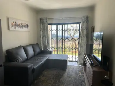 a living room with a couch and a large window at Luxury Apartment At Erand Gardens Midrand in Midrand